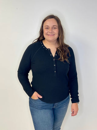Person wearing a dark blue long-sleeve shirt with buttons and jeans against a white background