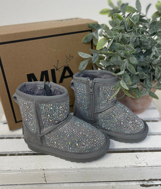 Gray children's boots with rhinestone details on a wooden surface with a plant and MIA Kids