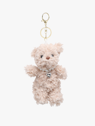 A beige fluffy teddy bear keychain charm with a gold-tone clasp, key ring, and a pearl collar with a silver heart charm, shown against a plain white background.