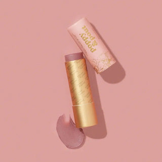 Lip balm tint with pink and gold packaging on a pink background