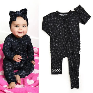 Baby wearing a black patterned onesie with a matching headband, next to the onesie on a white background.
