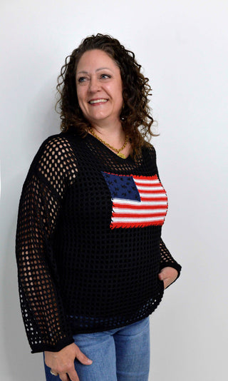 Woman wearing a black mesh top with an American flag design against a white background