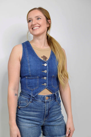 Woman wearing a blue denim vest and shorts on a plain background