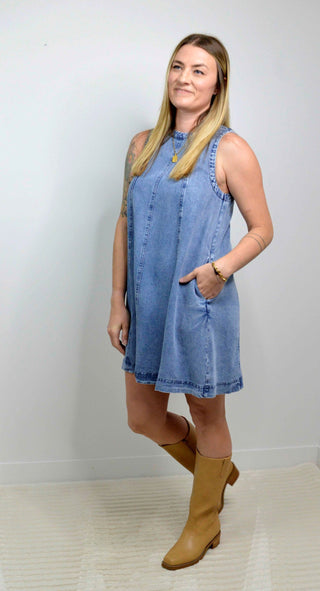Woman wearing a denim dress with yellow boots against a white background