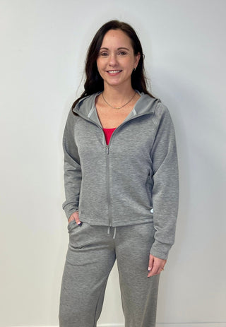 Woman wearing a gray tracksuit against a white background