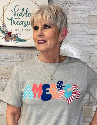 woman wearing a grey tshirt with America in different colors