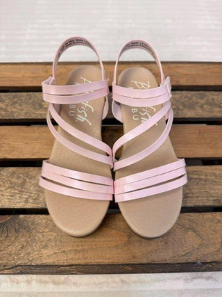 Pair of girls strappy sandals with pink straps on a wooden surface