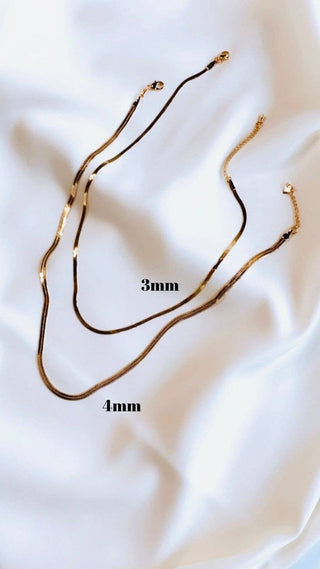 Two gold necklaces on a white fabric background with measurements indicated.