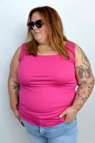 Person wearing a pink tank top and sunglasses against a white background