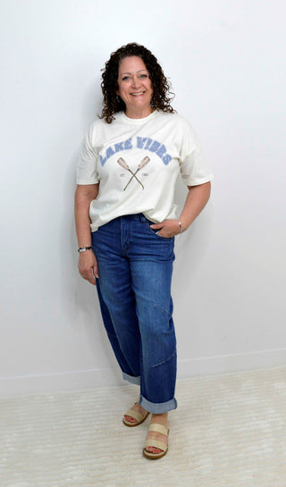 Woman wearing a white t-shirt with text and blue jeans against a plain background