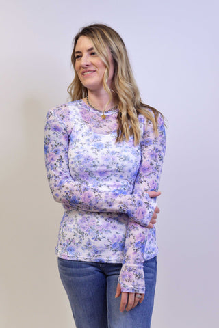 Woman wearing a floral long-sleeve top against a plain background