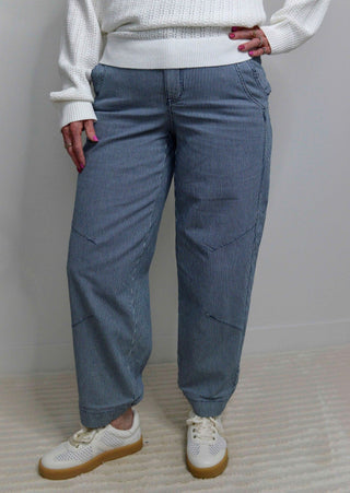 woman wearing navy pinstripe barrel pants with a white sweater