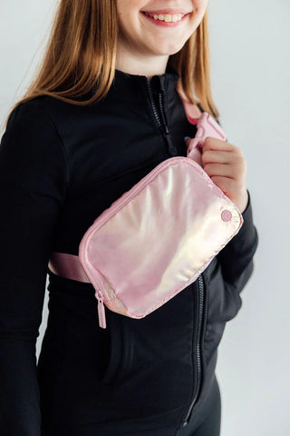 Girl wearing a pink fanny pack on a plain background