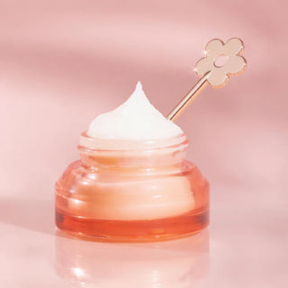 Jar of cream with a flower-shaped applicator on a pink background