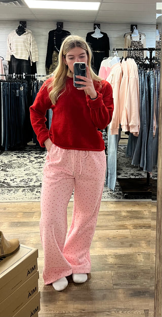 Person wearing a red sweater and pink pants in a clothing store.