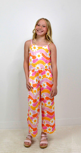 Young girl wearing a colorful floral jumpsuit on a white background