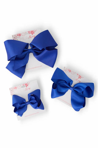 Two blue hair bows on a white background with floral patterns.