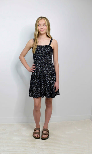 Young girl wearing a black floral dress against a white background