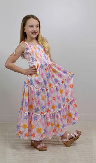 Young girl wearing a colorful floral dress on a plain background