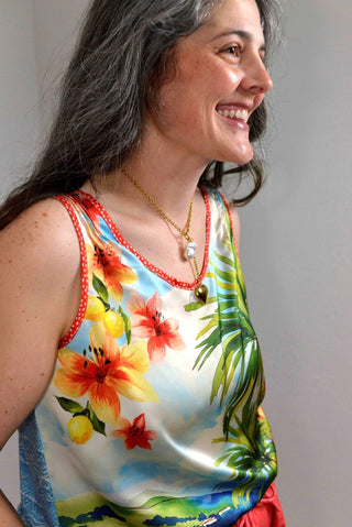 Woman wearing a colorful floral tank top against a plain background