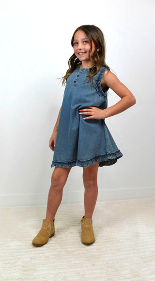 Young girl wearing a blue denim dress with yellow boots on a white background