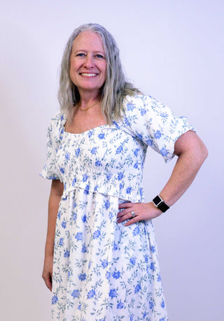 Woman wearing a floral dress against a plain background