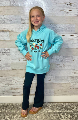 Young girl wearing a light blue hoodie with 'Lakegirl Forever' text and strawberry design on a wooden background.